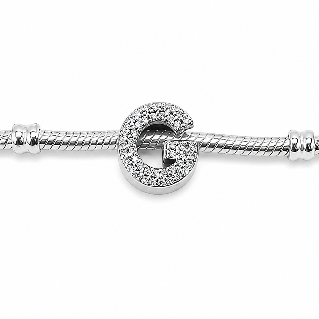 A silver-toned snake chain bracelet featuring a Sterling silver letter 'G' initial charm with cubic zirconia stones covering the front of the letter, shown on a plain white background.