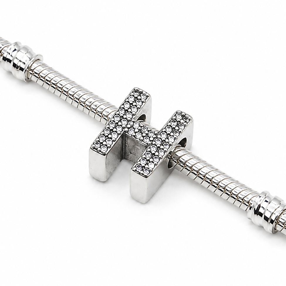 A silver-toned snake chain bracelet featuring a central letter 'H' charm paved with small clear stones, shown on a clean white background.