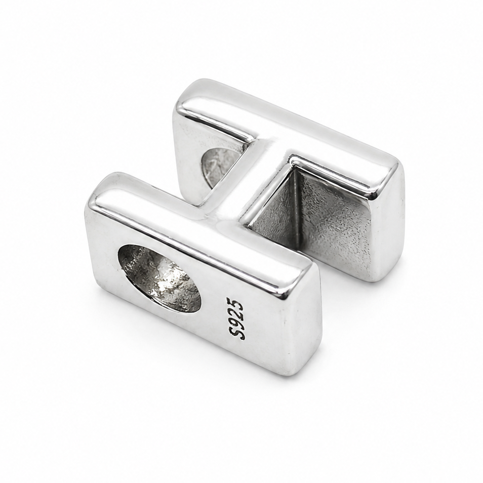 A sterling silver letter H charm photographed from the back with a polished finish and a '925' silver purity stamp on one end, shown on a clean white background.