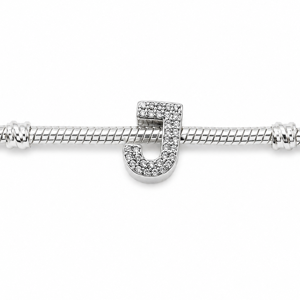 A silver snake chain bracelet featuring a polished sterling silver letter 'J' charm encrusted with small clear stones, shown against a plain white background.