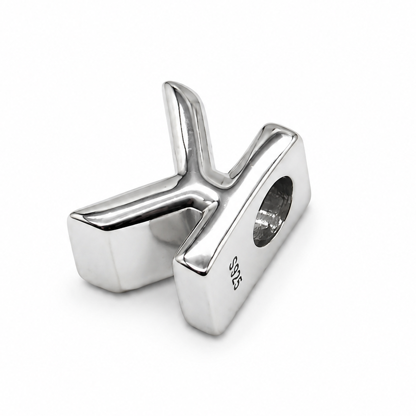 A sterling silver letter 'K' initial charm, photographed from the back which is polished sterling silver, shown on a plain white background.