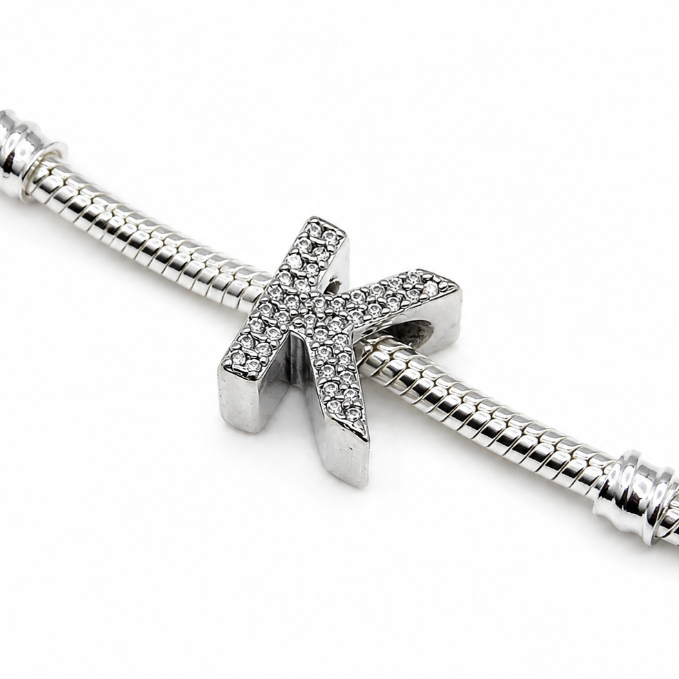 A silver snake chain bracelet featuring a sterling silver letter 'K' initial charm embellished with small clear pavé stones, shown on a plain white background.