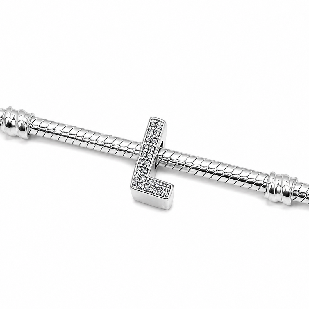 A silver snake chain bracelet featuring a sterling silver letter 'L' charm bead embellished with pavé-set clear crystals on a plain white background.