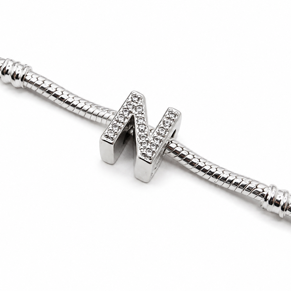 A silver snake chain bracelet featuring a polished letter 'N' charm encrusted with small clear stones, shown on a clean white background.