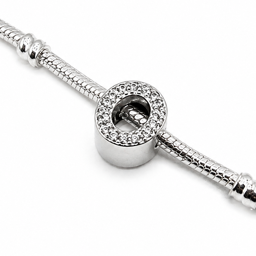 A silver snake chain bracelet featuring a sterling silver letter 'O' charm bead embellished with clear rhinestones and '925' silver purity stamp