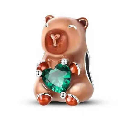 Capybara charm with a green gem on a white background